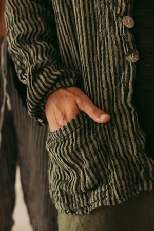 Close-up of a person wearing a ribbed blazer with buttons, focusing on the sleeve and hand.