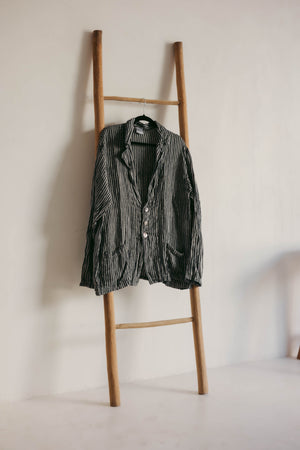 Striped shirt hanging on a wooden ladder against a plain wall