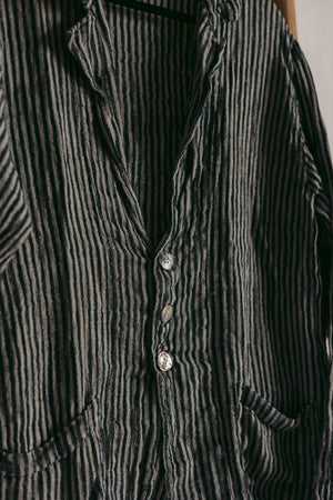 Close-up of a dark gray striped linen blazer with buttons on a plain background