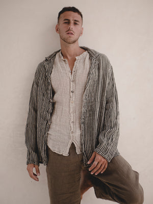 Man wearing a striped blazer over a button-up shirt with a neutral background