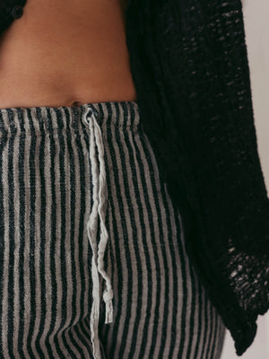Close-up of striped pants with a black textured cardigan.