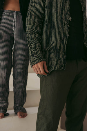 Two people wearing striped linen blazer and pants in a neutral setting