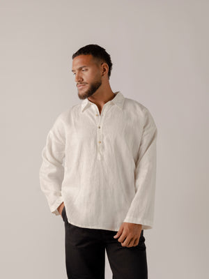 A male model wearing a white, long-sleeved, half-button placket collar shirt made of linen.