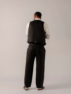 A model wearing black classic fit straight-line trousers with pockets on the sides and behind, and subtle pleat detailing from the waistband.