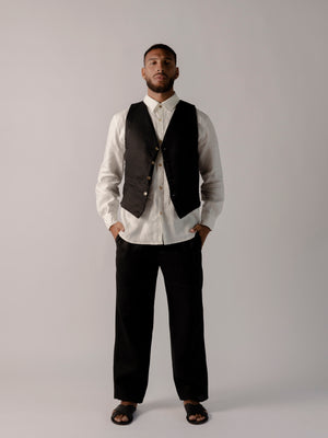 A model wearing black classic fit straight-line trousers with pockets on the sides and behind, and subtle pleat detailing from the waistband.