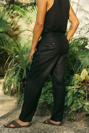 A model wearing black classic fit straight-line trousers with pockets on the sides and behind, and subtle pleat detailing from the waistband.