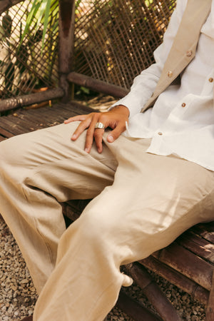 Person wearing a white shirt and beige pants sitting on a wooden bench.