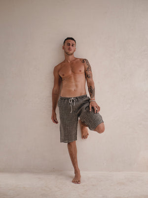 Man wearing gray shorts standing against a plain background