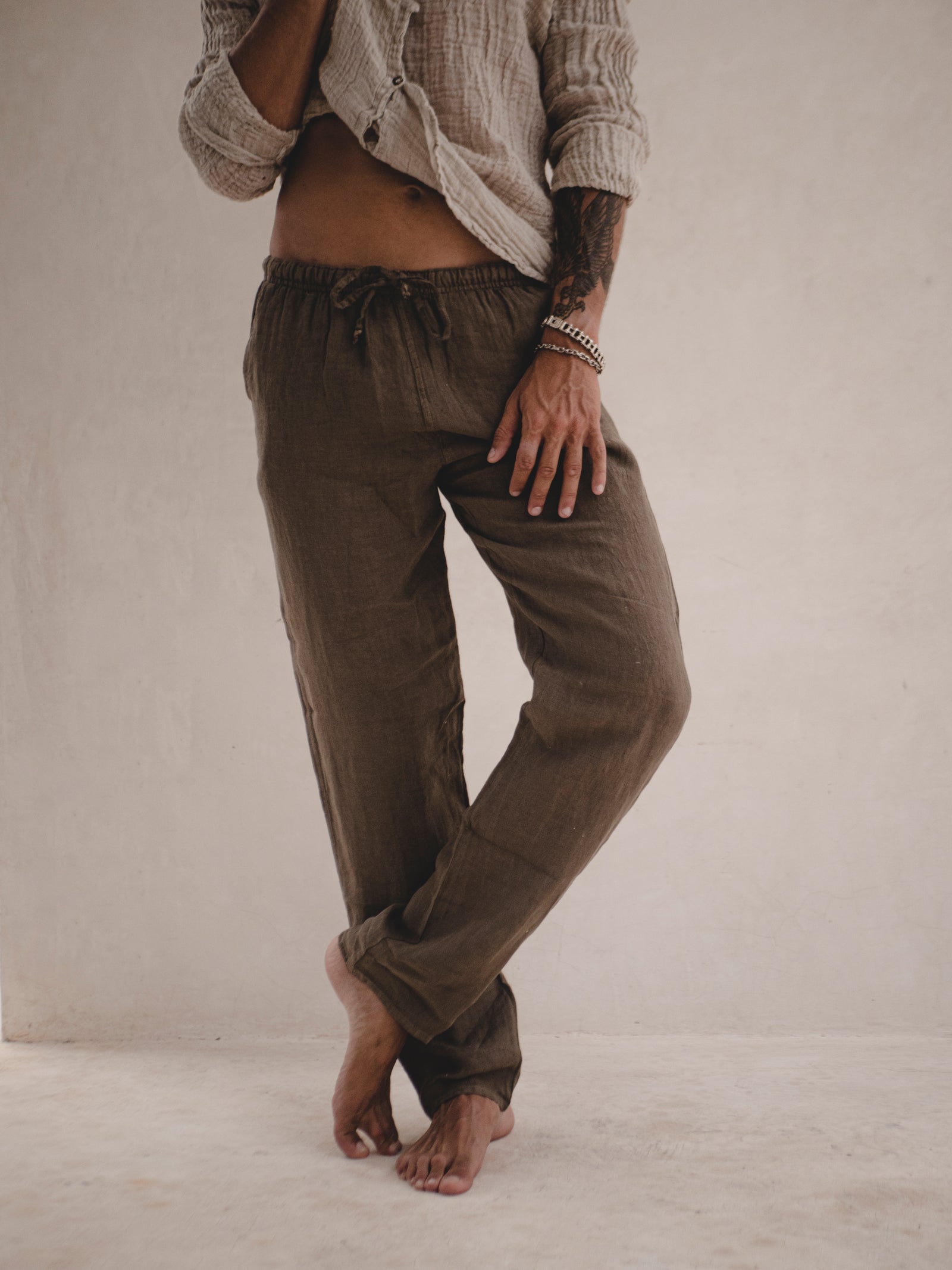Person wearing brown pants and a beige shirt against a plain background