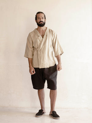 man wearing a black linen oversized bermuda with a khaki kimono