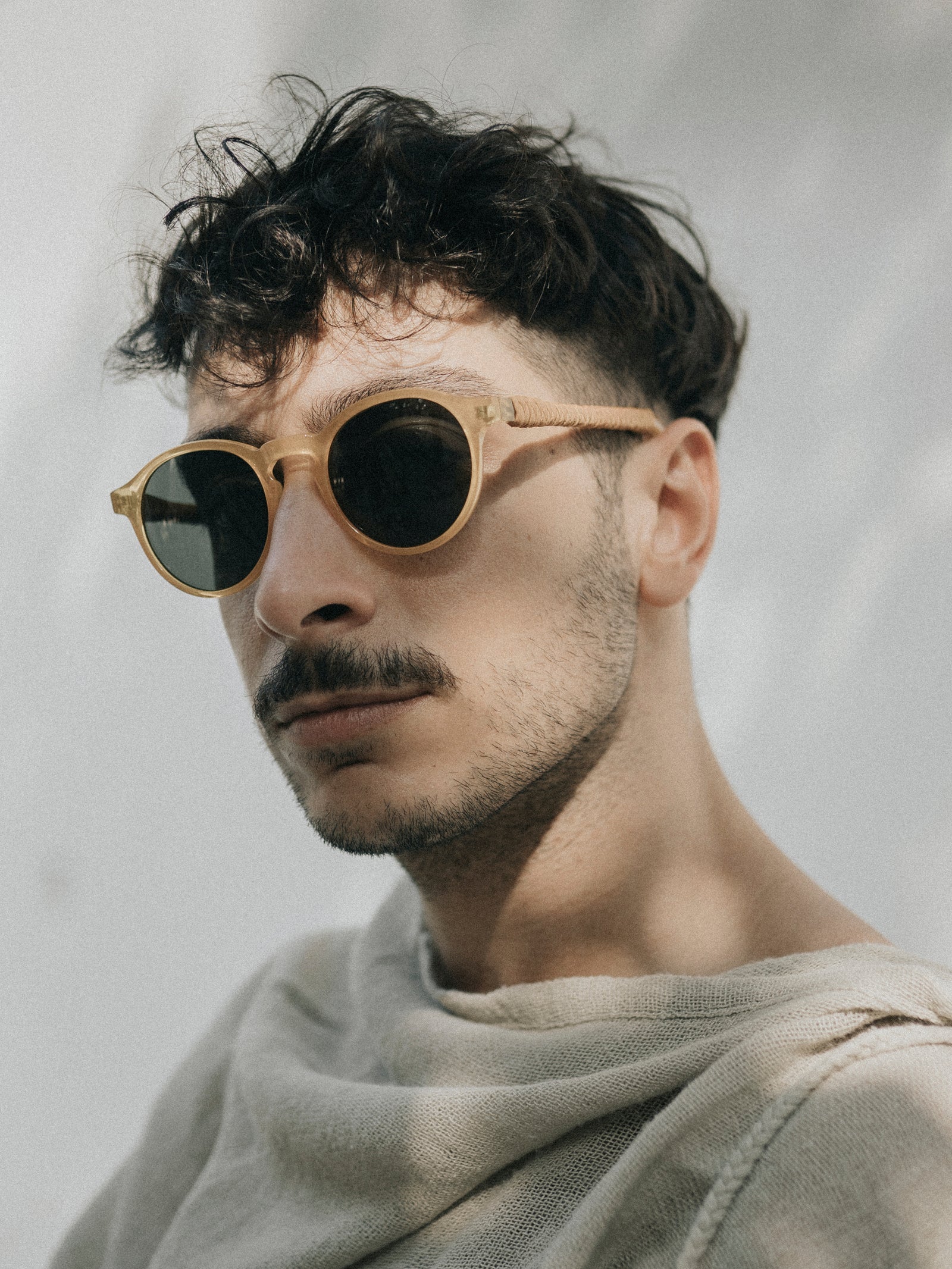 Man wearing round sunglasses with a neutral background