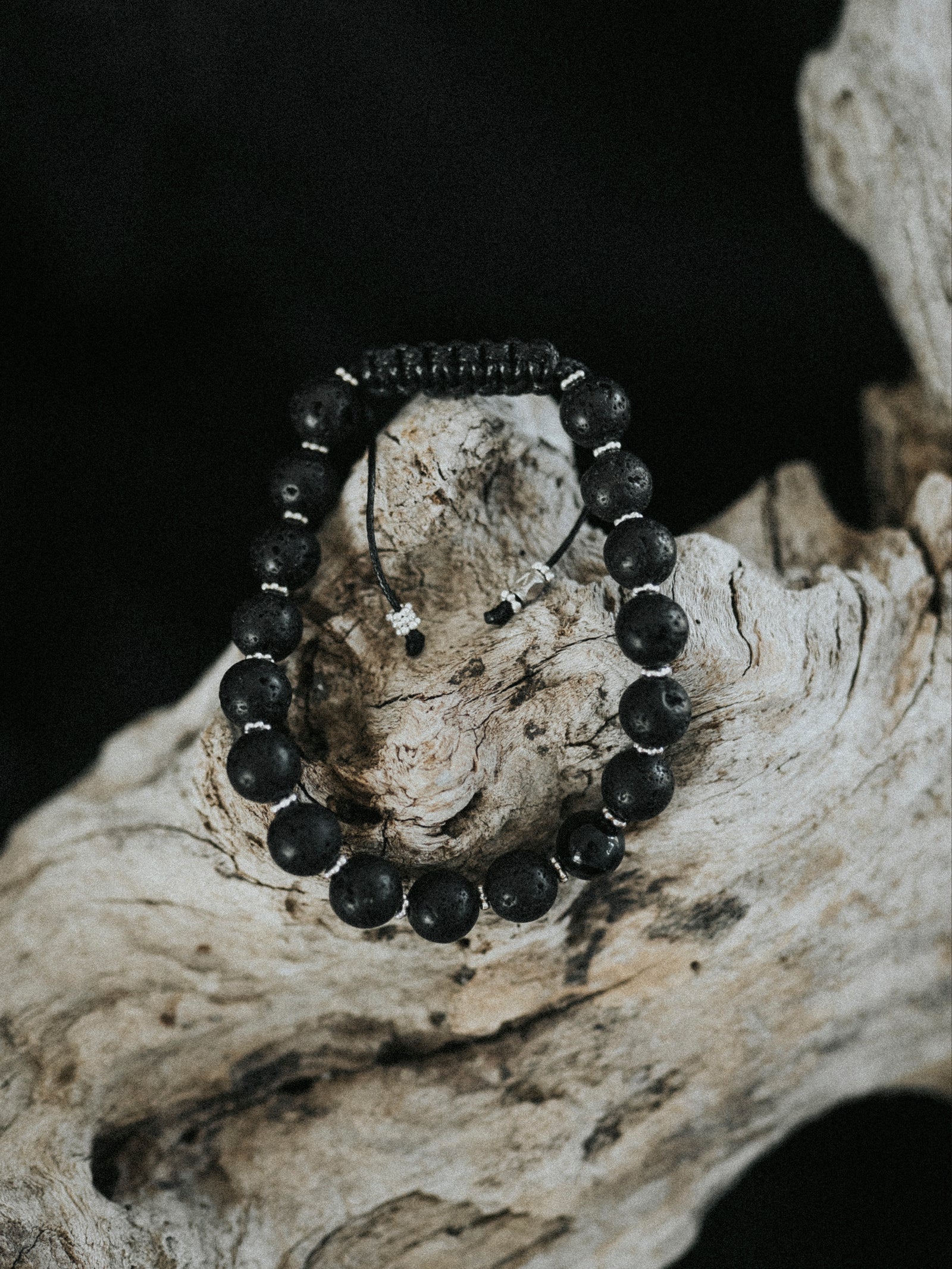 Black beaded bracelet on a piece of driftwood with a dark background