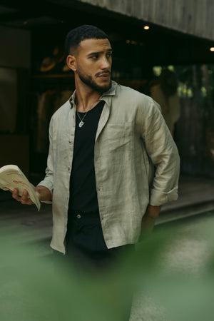 A person wearing a long sleeve khaki linen shirt with the collar buttoned up.