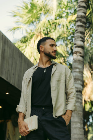 A person wearing a long sleeve khaki linen shirt with the collar buttoned up.