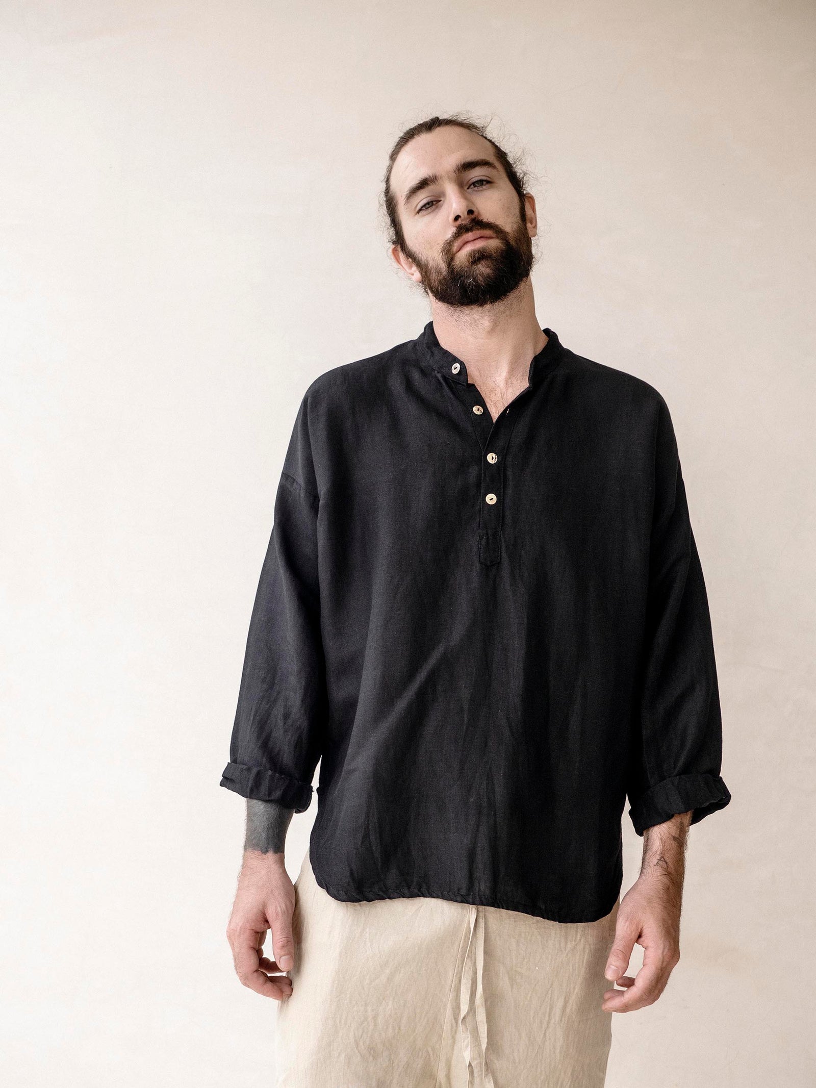 Man wearing a black linen shirt with  loose fit and mandarin collar