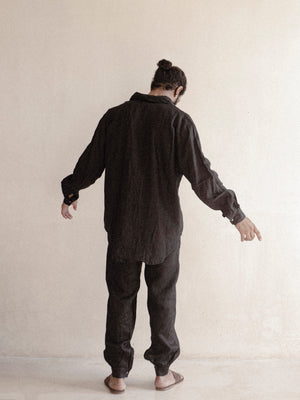 A man wearing a black oversized shirt with long sleeves.