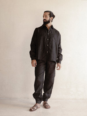 A man wearing a black oversized shirt with long sleeves.