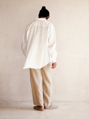 A man wearing a white oversized shirt with long sleeves.