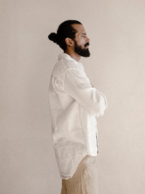 A man wearing a white oversized shirt with long sleeves.