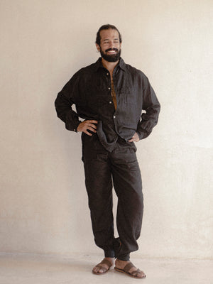 A man wearing a black oversized shirt with long sleeves.
