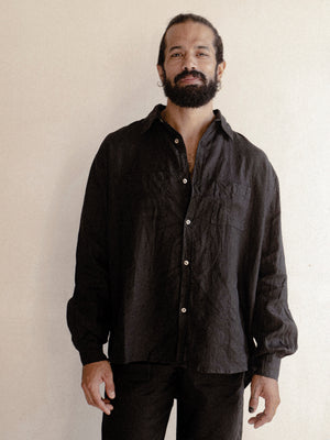 A man wearing a black oversized shirt with long sleeves.