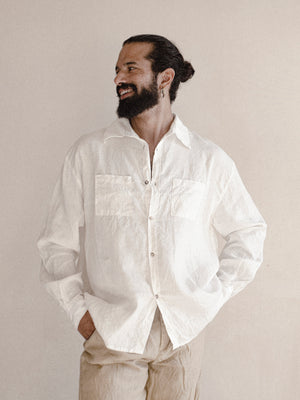 A man wearing a white oversized shirt with long sleeves.
