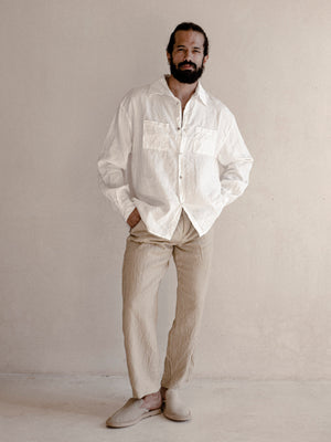 A man wearing a white oversized shirt with long sleeves.