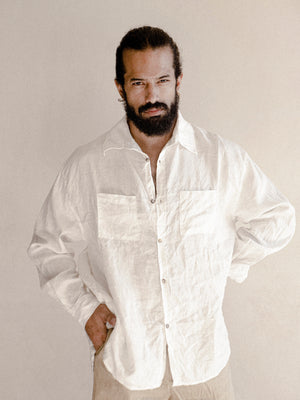 A man wearing a white oversized shirt with long sleeves.