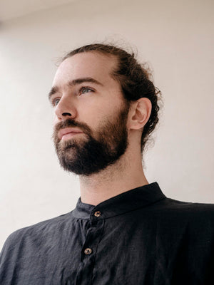 A man wearing a beige linen mandarin collar buttoned-down shirt with long sleeves, displaying a loose fit and buttoned cuffs - IN THE MIDDLE