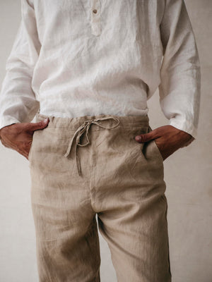 A pair of men's linen jogger pants in khaki, with an elasticized drawstring waist and side pockets. 