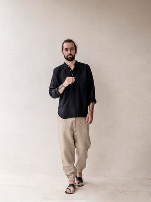 A pair of men's linen jogger pants in khaki, with an elasticized drawstring waist and side pockets. 