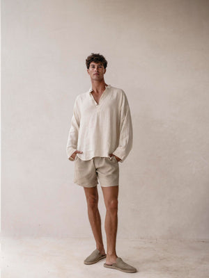A man wearing khaki linen bermuda shorts with elasticized waist and side pockets. 