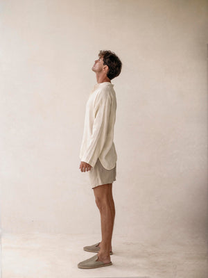A man wearing khaki linen bermuda shorts with elasticized waist and side pockets. 