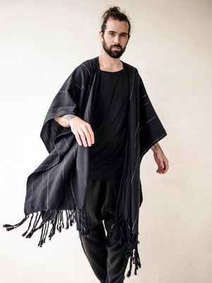 Oversized black cotton cape poncho for men with hand-finished fringe. Lightweight breathable cover up for beachwear, vacations and relaxed resort style.