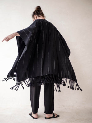 Oversized black cotton cape poncho for men with hand-finished fringe. Lightweight breathable cover up for beachwear, vacations and relaxed resort style.