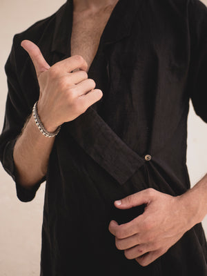 A person wearing a black kimono with 3/4 sleeves and a collar lapel, standing against a neutral background.