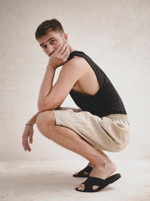 man wearing a linen oversized bermuda with a black cotton tank top